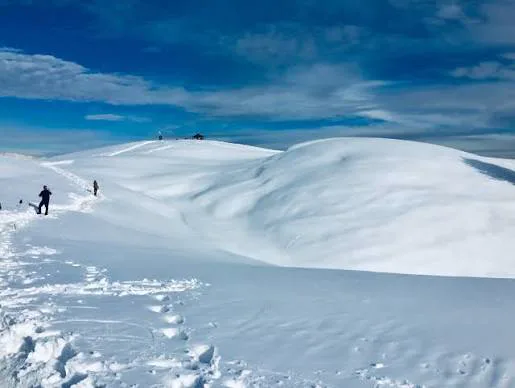 Wide snowy mountain landscape with distant trekkers