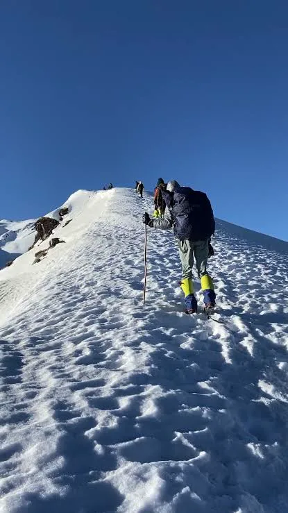 Trekker carrying a backpack and walking pole on a snowy ascent